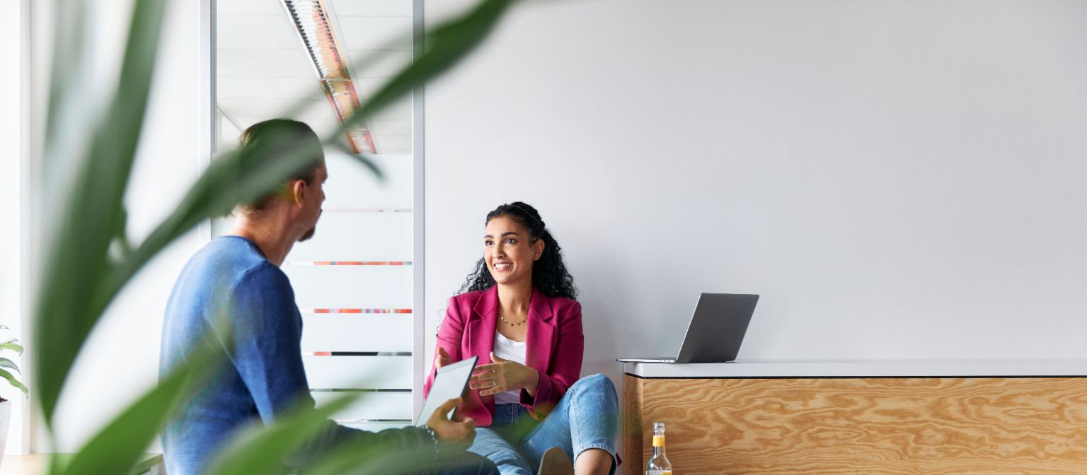A man and a woman having a relaxed-looking conversation, as a symbolic image of a corporate culture where employees have autonomy.