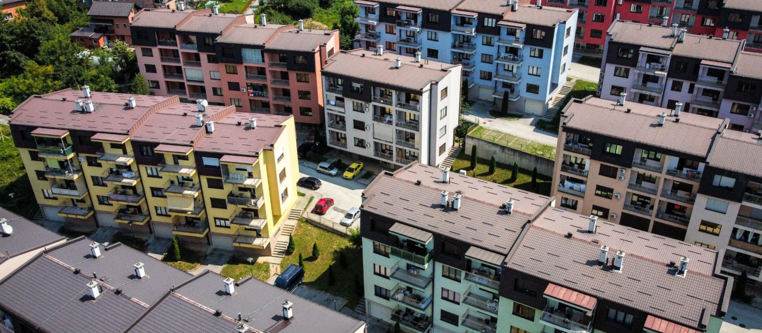 NPL, обезпечени с недвижими имоти: въздушен изглед на оживен жилищен комплекс с многоцветни сгради, заобиколени от зелени площи в Босна и Херцеговина