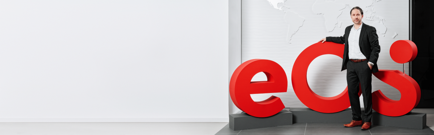 Marwin Ramcke, CEO of the EOS Group, stands in front of a large 3D model of the red company logo<br/>