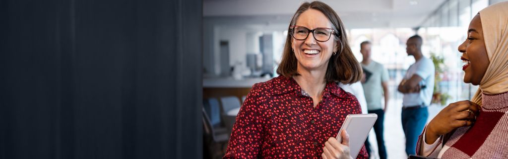 Две щастливи жени водят непринуден офис разговор