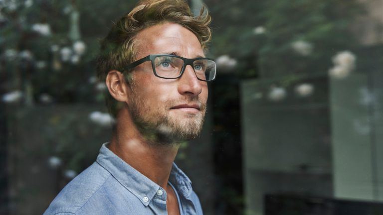 Млад мъж от поколение Z наднича тревожно през прозореца.