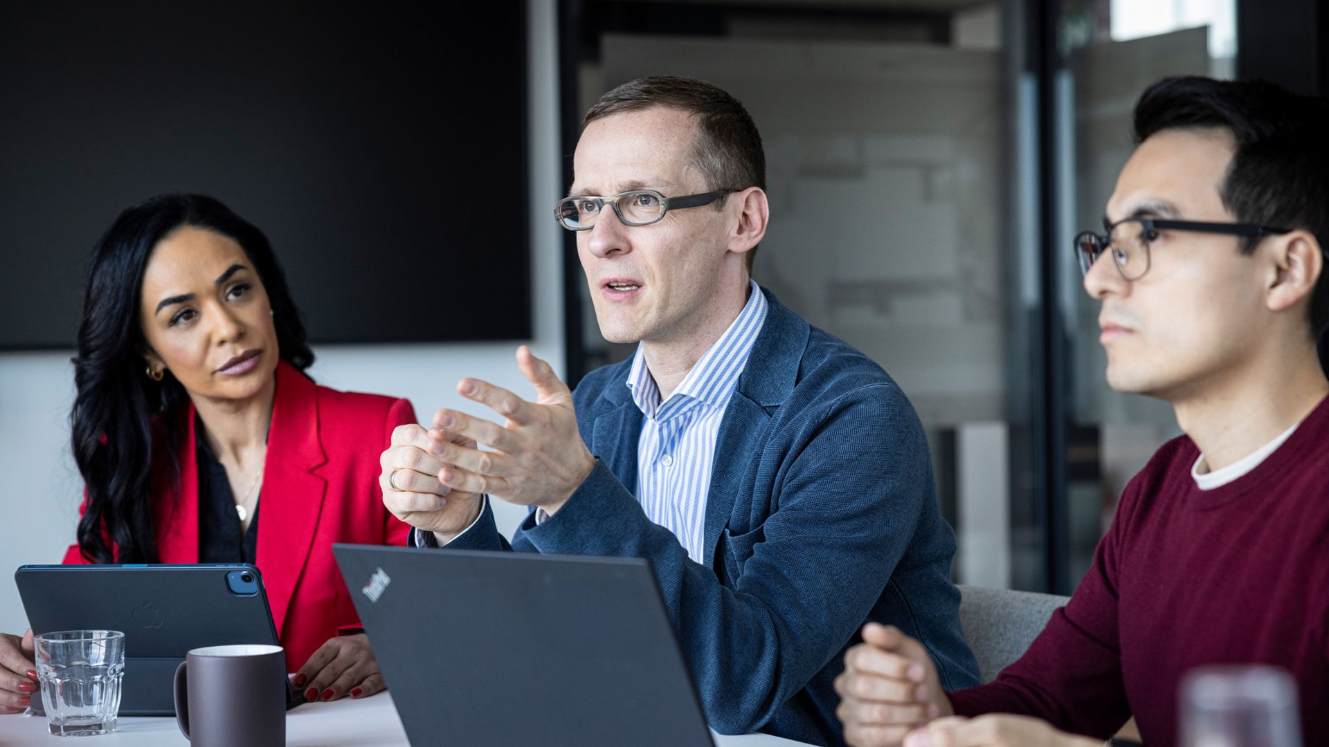 трима души разговарят в офис.