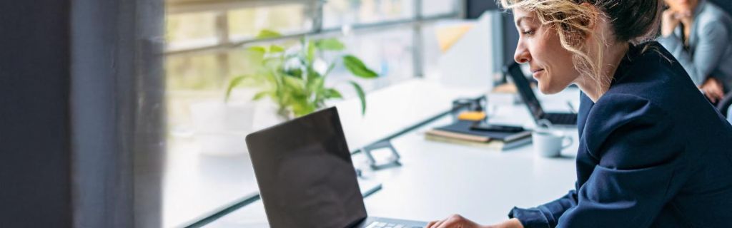 Млада жена работи на лаптоп в модерен офис.