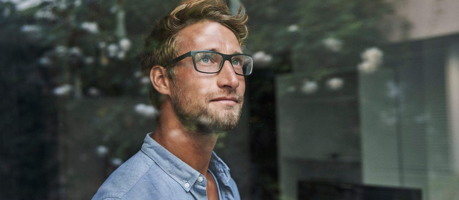 Млад мъж от поколение Z наднича тревожно през прозореца.